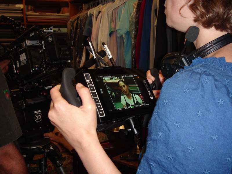 Holding an on-set monitor with wardrobe racks in the background
