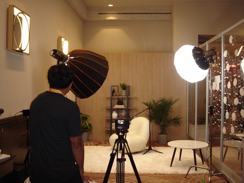 Crew member positioning a light in a bright, plant-filled room