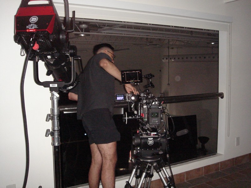 Camera rig set up by a large window, operator adjusting the shot
