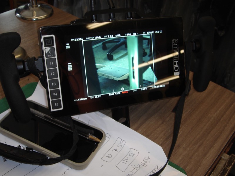 Close-up of an on-set monitor screen with notes on the table below