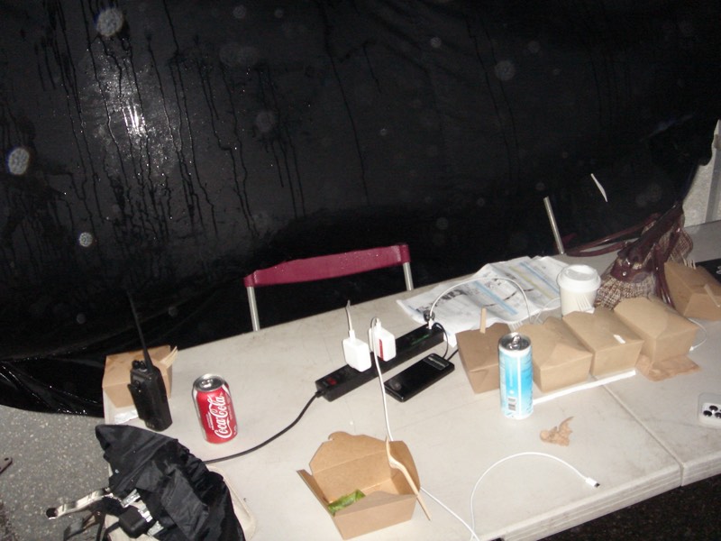 Folding table with takeout food boxes and a Coke can between takes