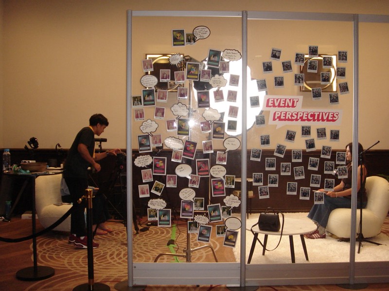 Crew member at a desk beneath a wall of reference photos and notes