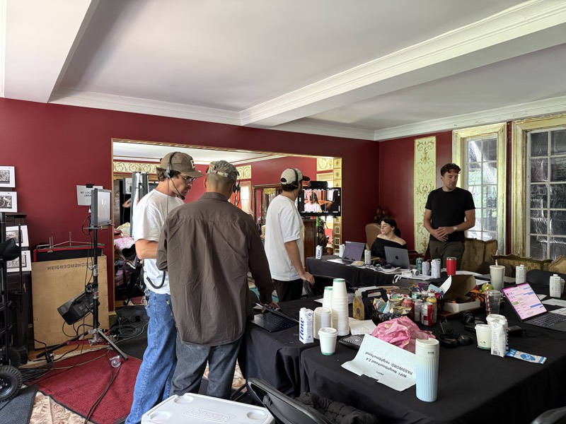 Staging room with red walls, crew working around a table of supplies and monitors