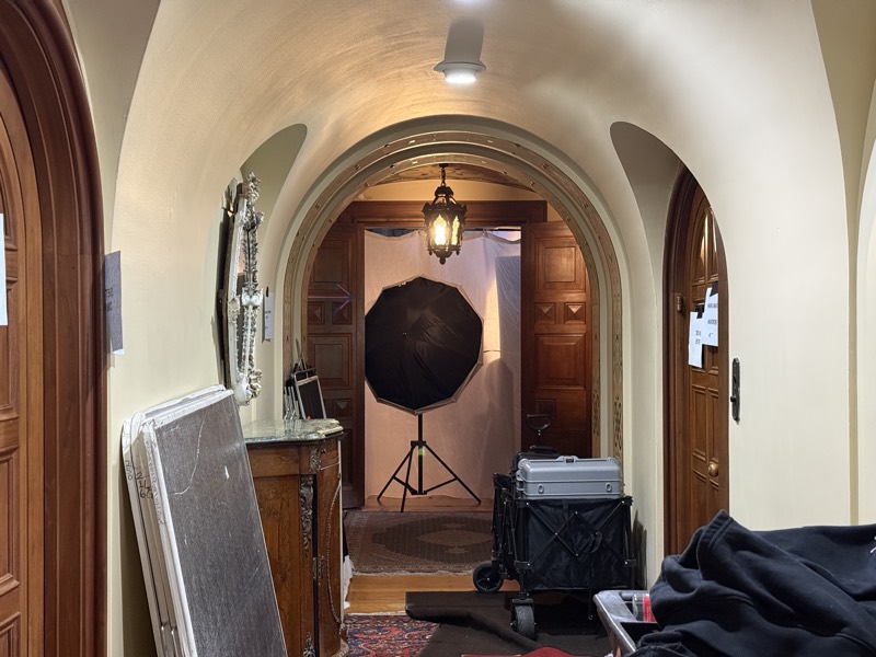 Arched hallway of an old house looking through to a lighting setup in the room beyond