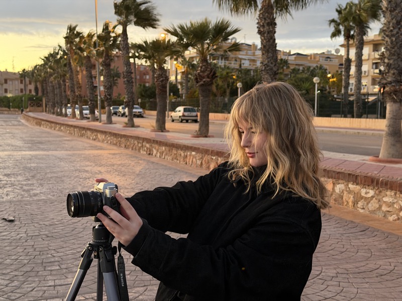 Filming at golden hour on a palm-lined promenade, camera on a tripod